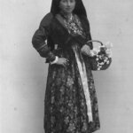 Bewohnerin in traditioneller Tracht mit Spitzhut und Schürze